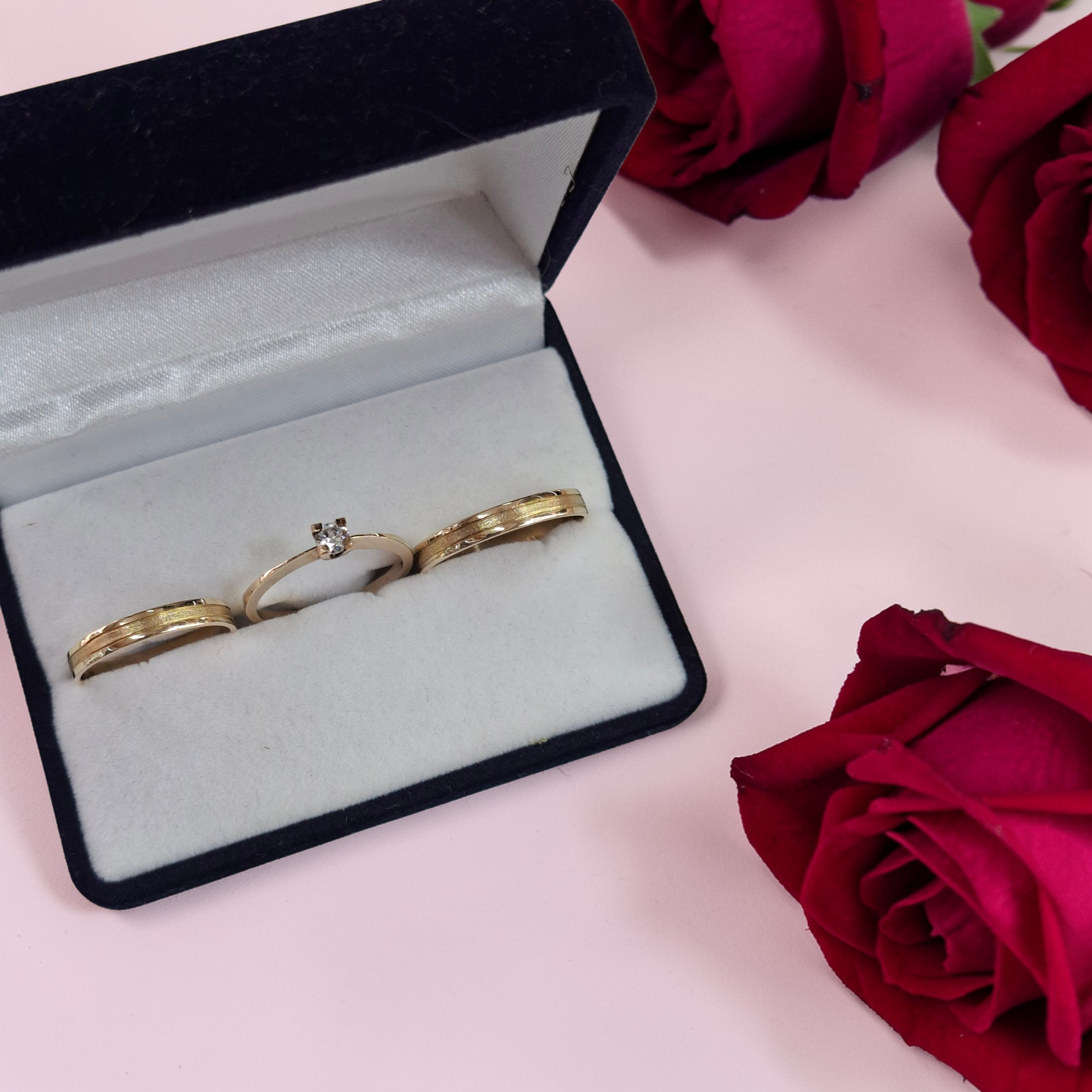 Alianzas de oro en su estuche, junto a rosas